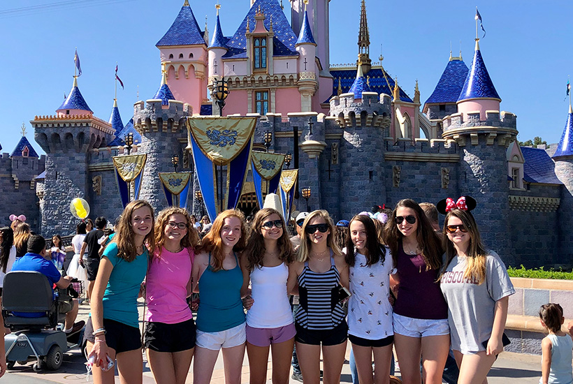 teen girls standing in front of a castle at Disneyland